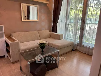 Cozy living room with elegant sofa and glass coffee table, featuring large windows for natural light.