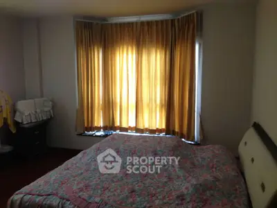 Cozy bedroom with floral bedding and warm curtains, perfect for relaxation.
