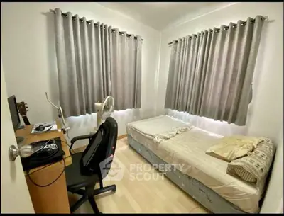 Cozy bedroom with natural light, featuring a bed, desk, and chair, ideal for a comfortable living space.