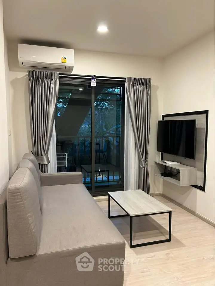 Modern living room with sleek furniture and balcony view, featuring a wall-mounted TV and air conditioning.
