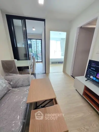 Modern apartment interior with open living room and dining area, featuring a stylish sofa and wooden flooring.