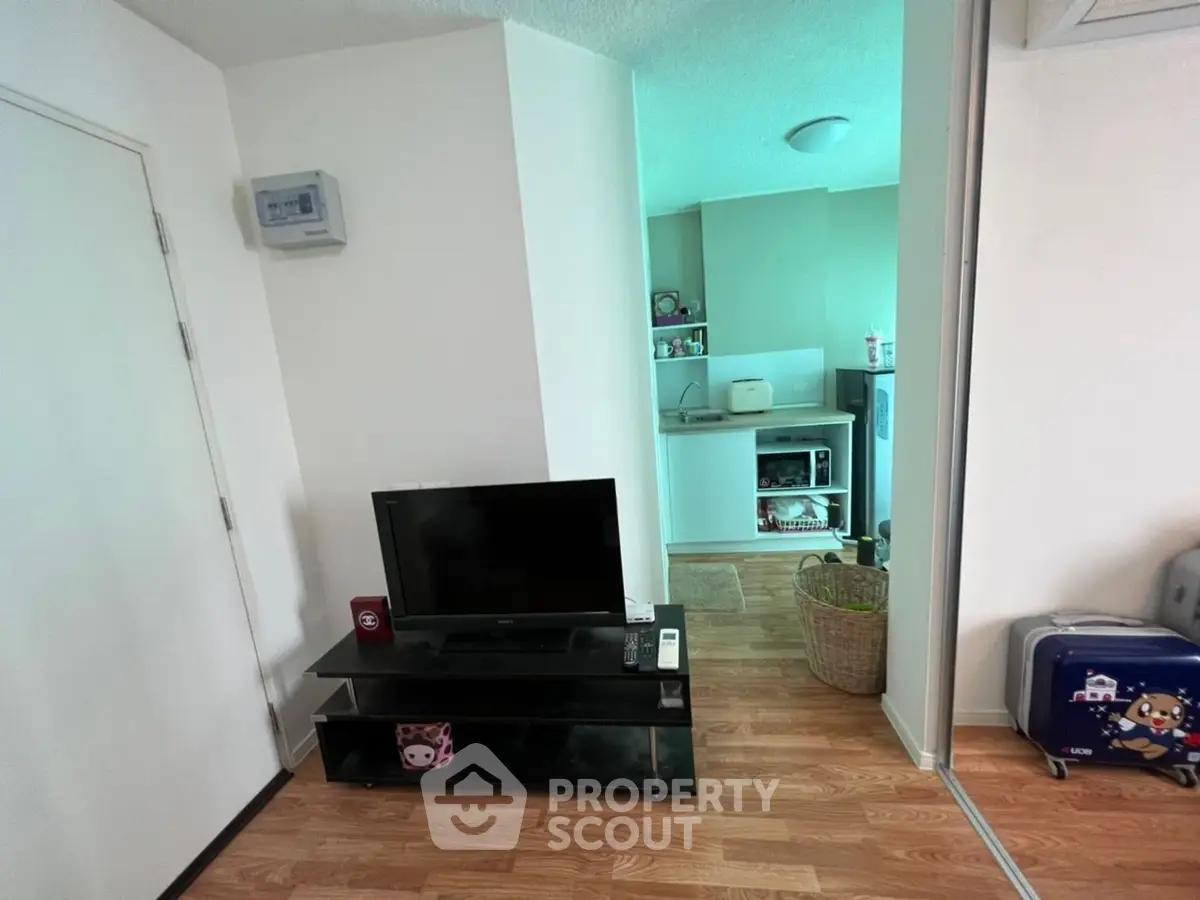 Cozy apartment interior with compact kitchen and living area, featuring modern appliances and wooden flooring.
