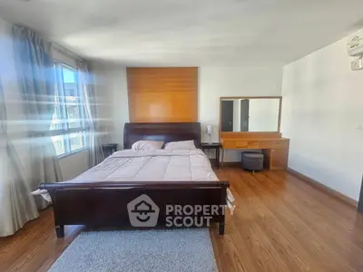 Spacious bedroom with wooden flooring and large window for natural light