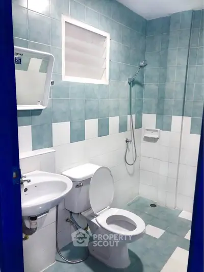 Modern bathroom with blue and white tiles, featuring a shower and toilet in a compact layout.