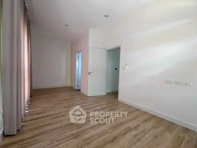 Spacious empty room with wooden flooring and natural light