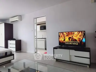 Modern apartment interior with open layout and sleek furniture, featuring a TV and air conditioning.