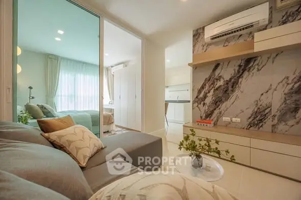 Modern living room with stylish decor and open view to bedroom, featuring elegant furnishings and natural light.