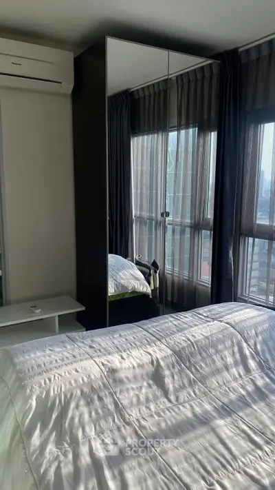 Modern bedroom with large windows and mirrored wardrobe reflecting natural light.
