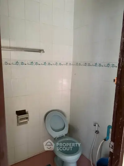 Compact bathroom with basic fixtures and tiled walls
