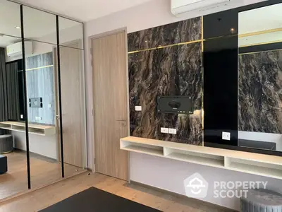 Modern minimalist living room with elegant marble wall accents, sleek built-in shelving, and mirrored wardrobe doors enhancing the spacious feel.