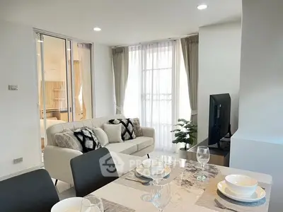 Modern living room with elegant dining area and cozy seating, featuring natural light and stylish decor.