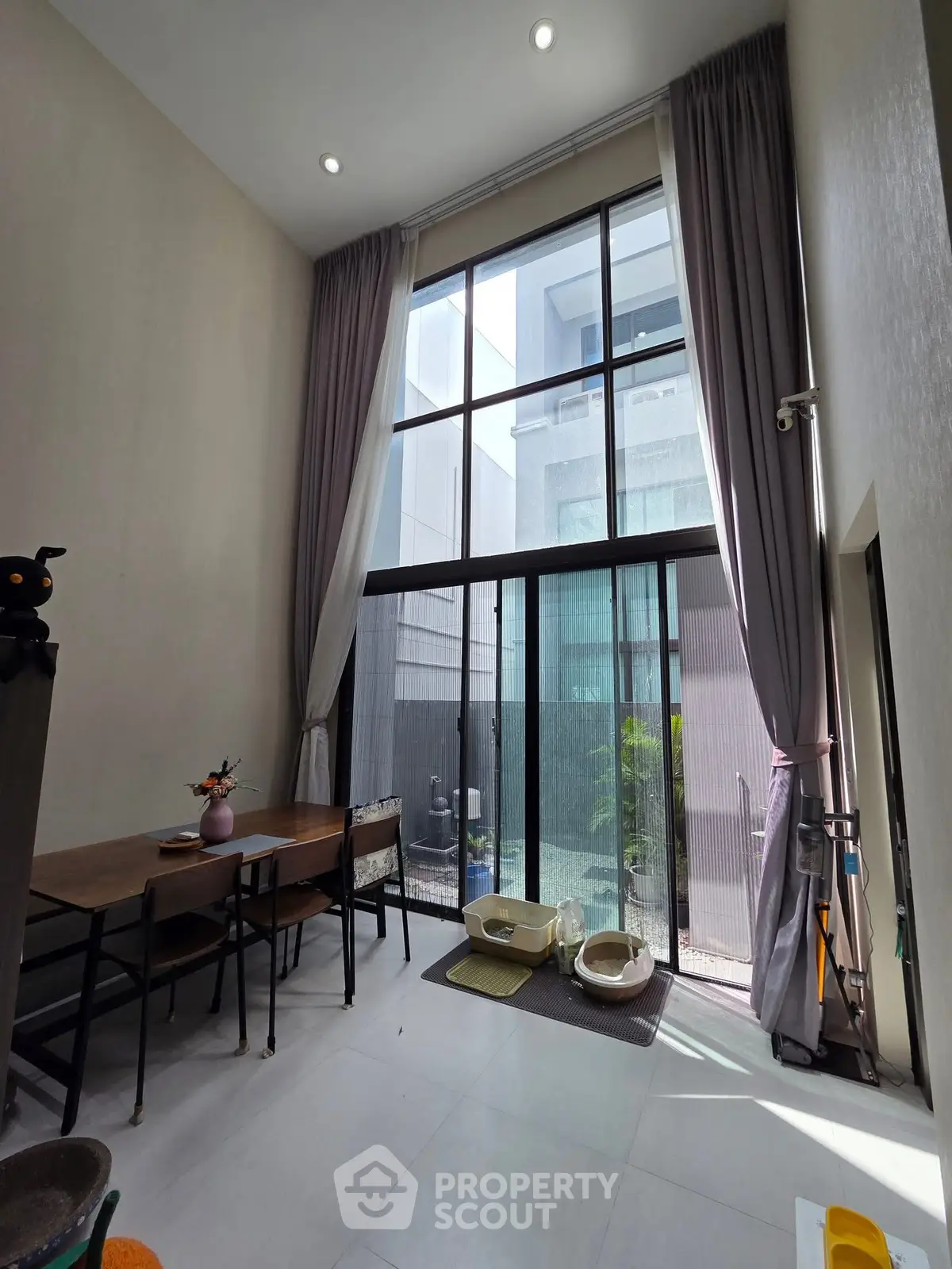 Spacious modern living room with high ceilings and large windows, offering abundant natural light and a stylish interior.