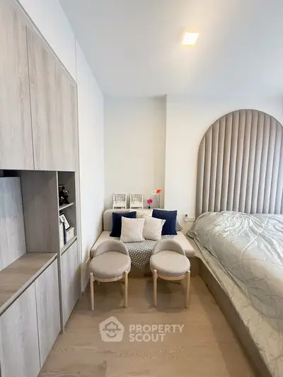 Modern bedroom with stylish decor and cozy seating area, featuring neutral tones and elegant design.