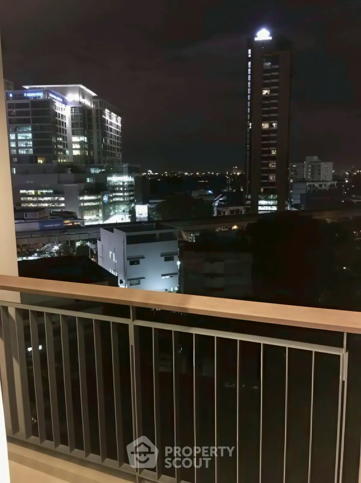 Stunning night cityscape view from a modern apartment balcony, showcasing urban skyline.