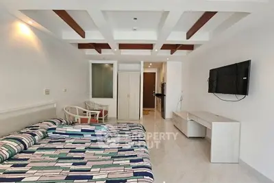Modern bedroom with stylish ceiling design, wall-mounted TV, and cozy seating area.
