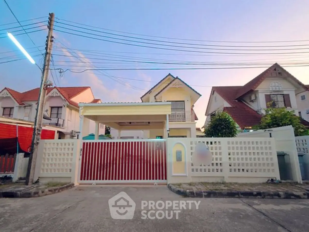 Charming suburban house with gated entrance and spacious driveway at sunset.