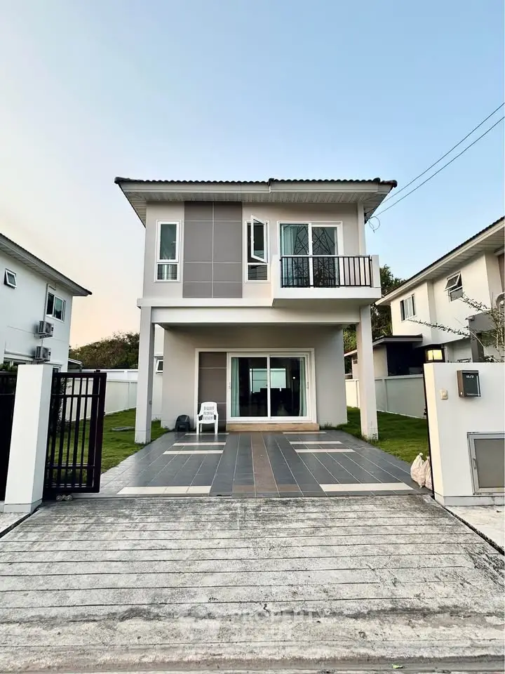 Modern two-story house with balcony and spacious driveway in a serene neighborhood.