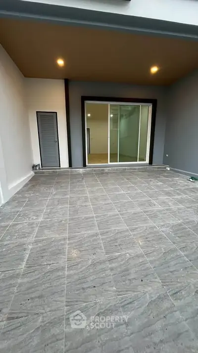 Spacious tiled patio with sliding glass doors leading to interior space