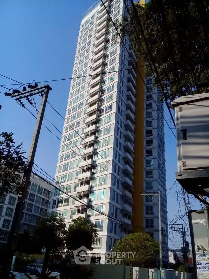 Modern high-rise residential building with glass balconies and urban surroundings.