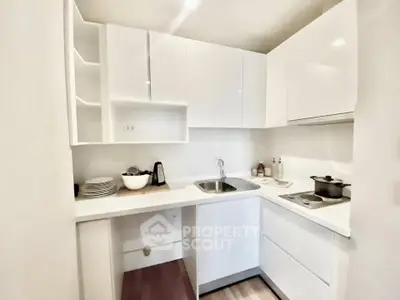 Modern compact kitchen with sleek white cabinets and integrated appliances in a stylish apartment.