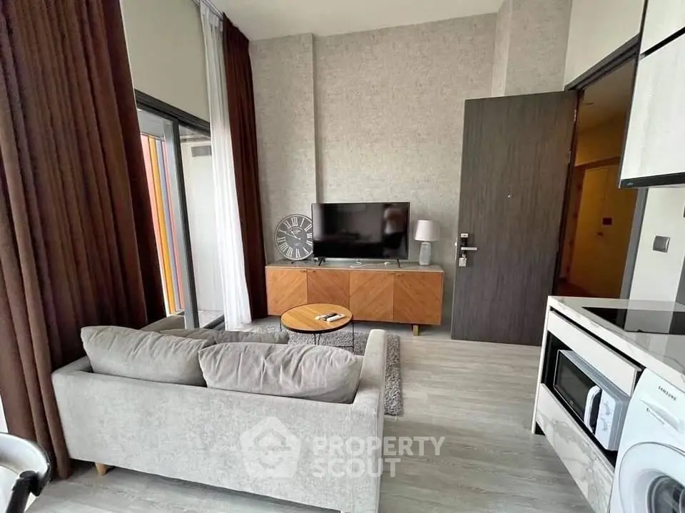 Modern living room with sleek furniture and large TV, featuring open layout and stylish decor.