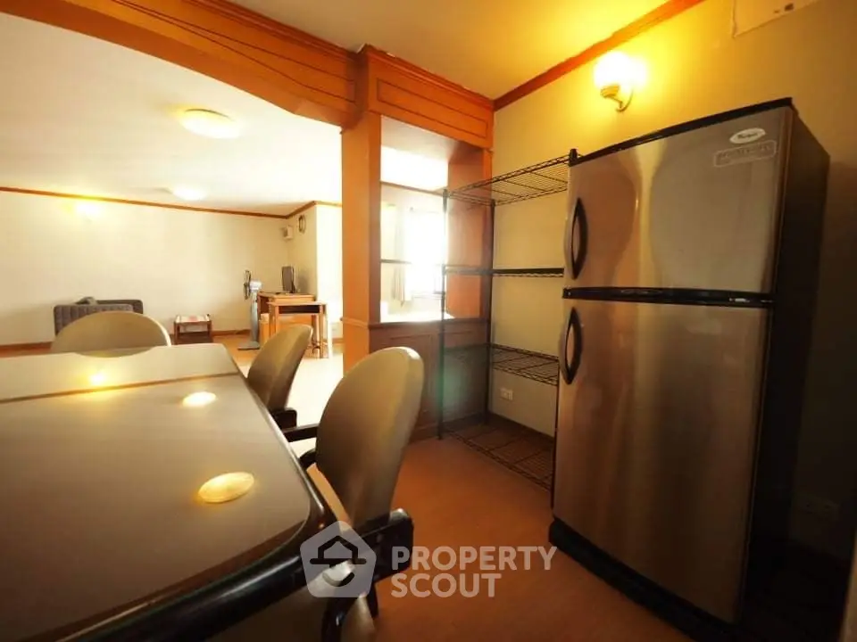Spacious kitchen with stainless steel fridge and dining area in modern apartment.