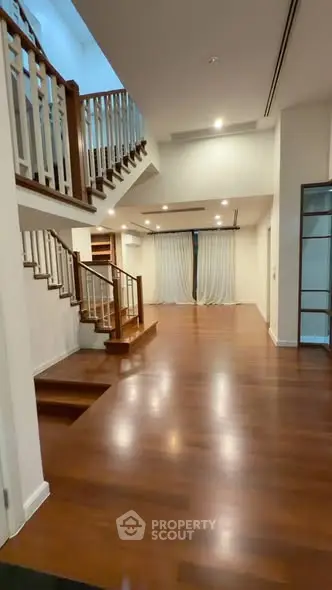 Spacious open-concept living area with elegant wooden flooring and staircase