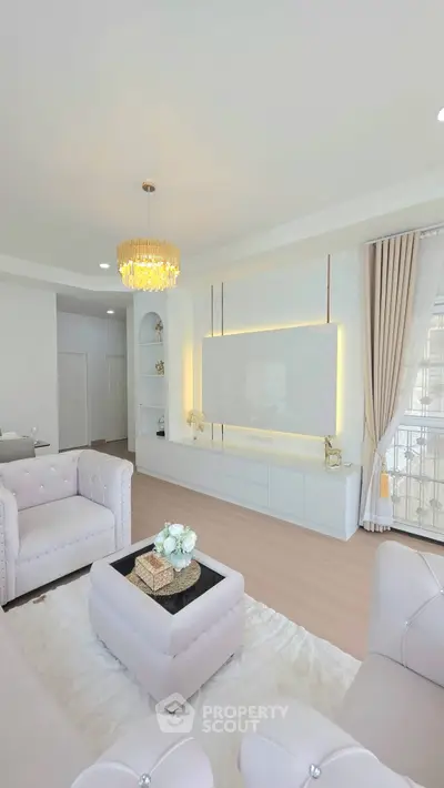 Luxurious modern living room with elegant chandelier and plush seating in a bright, airy space.