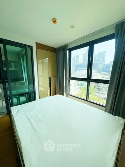 Modern bedroom with large windows and city view, featuring sleek design and natural light.