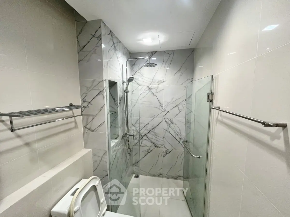 Modern bathroom with marble tiles and glass shower enclosure