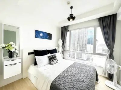 Bright modern bedroom with city view, featuring stylish decor and large windows for natural light.