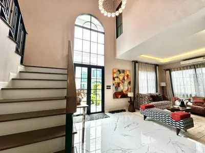 Luxurious living room with high ceilings, elegant staircase, and modern decor