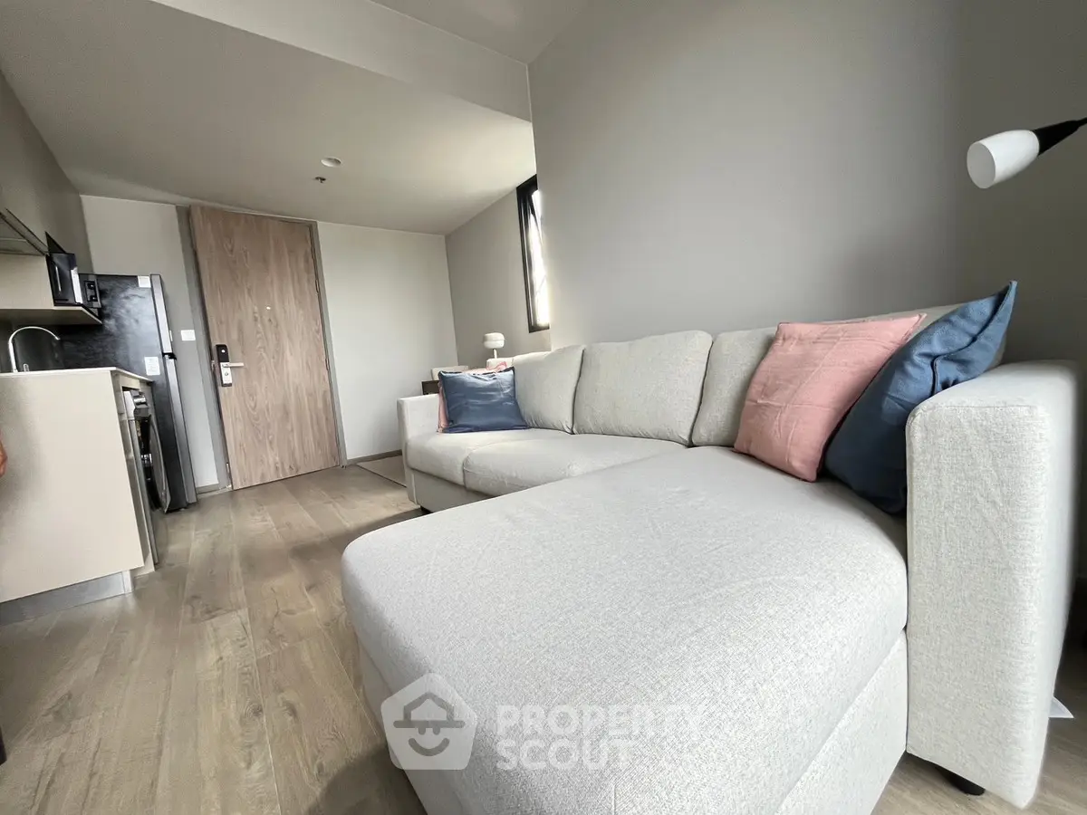 Modern living room with stylish sofa and kitchenette in open layout apartment.