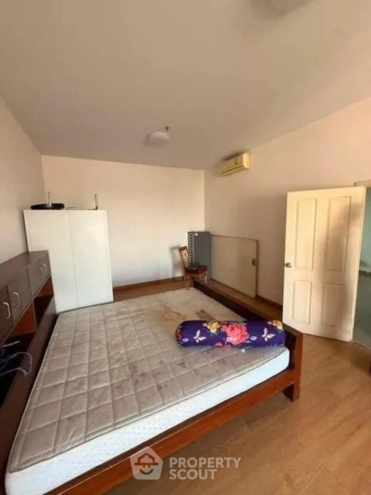 Spacious bedroom with wooden flooring and ample natural light, featuring a large bed and modern wardrobe.