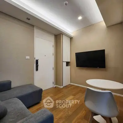 Modern living room with sleek furniture and wall-mounted TV, featuring wooden flooring and neutral tones.