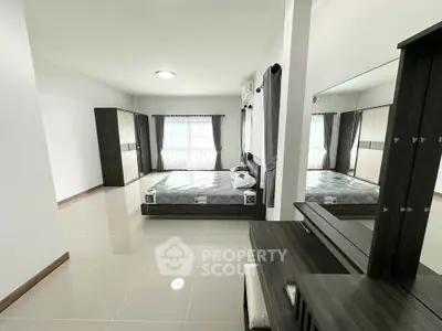 Spacious modern bedroom with sleek furniture and large windows for natural light.