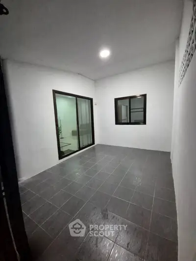 Spacious interior room with tiled flooring and large window, perfect for versatile use.