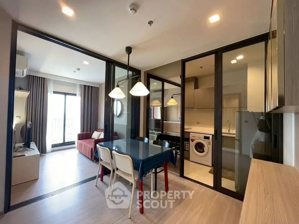 Modern apartment interior with open layout, featuring dining area, living room, and laundry space.