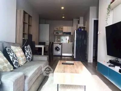 Modern living room with open kitchen, featuring a washing machine and sleek appliances.