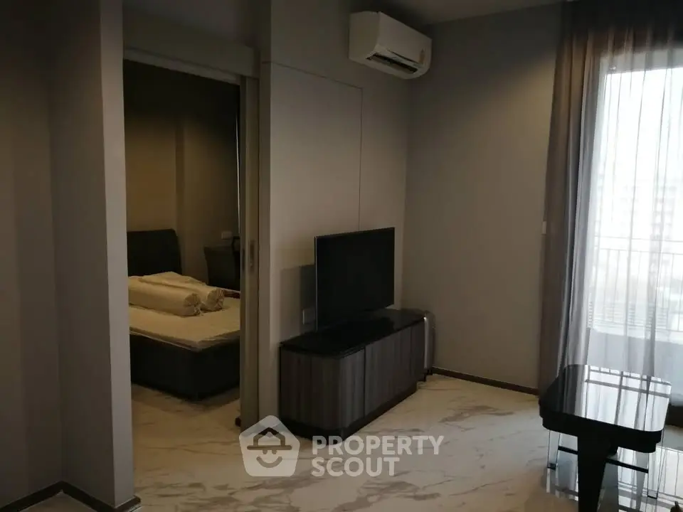 Modern living room with sleek TV stand and view into cozy bedroom