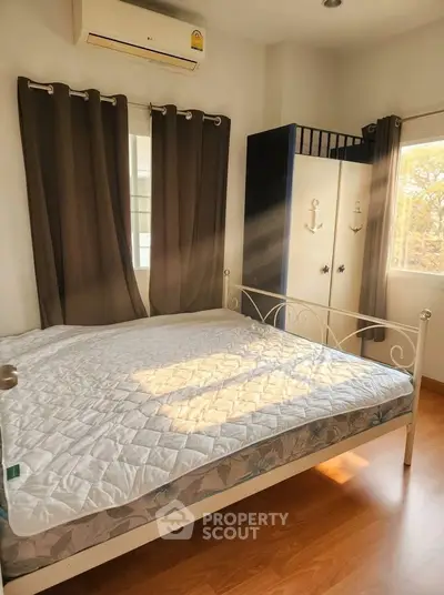 Cozy bedroom with natural light, featuring a stylish bed and modern wardrobe, perfect for relaxation.