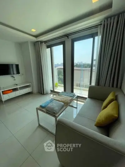 Bright living room with large windows and modern decor, offering a cozy and inviting atmosphere.
