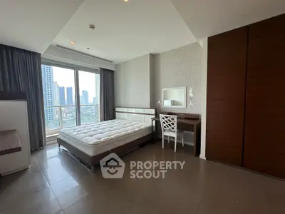 Spacious bedroom with city view and modern furnishings in high-rise apartment.