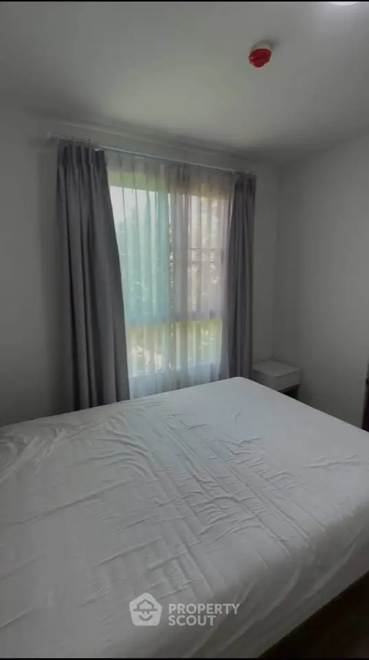 Cozy bedroom with natural light and elegant curtains, perfect for relaxation.