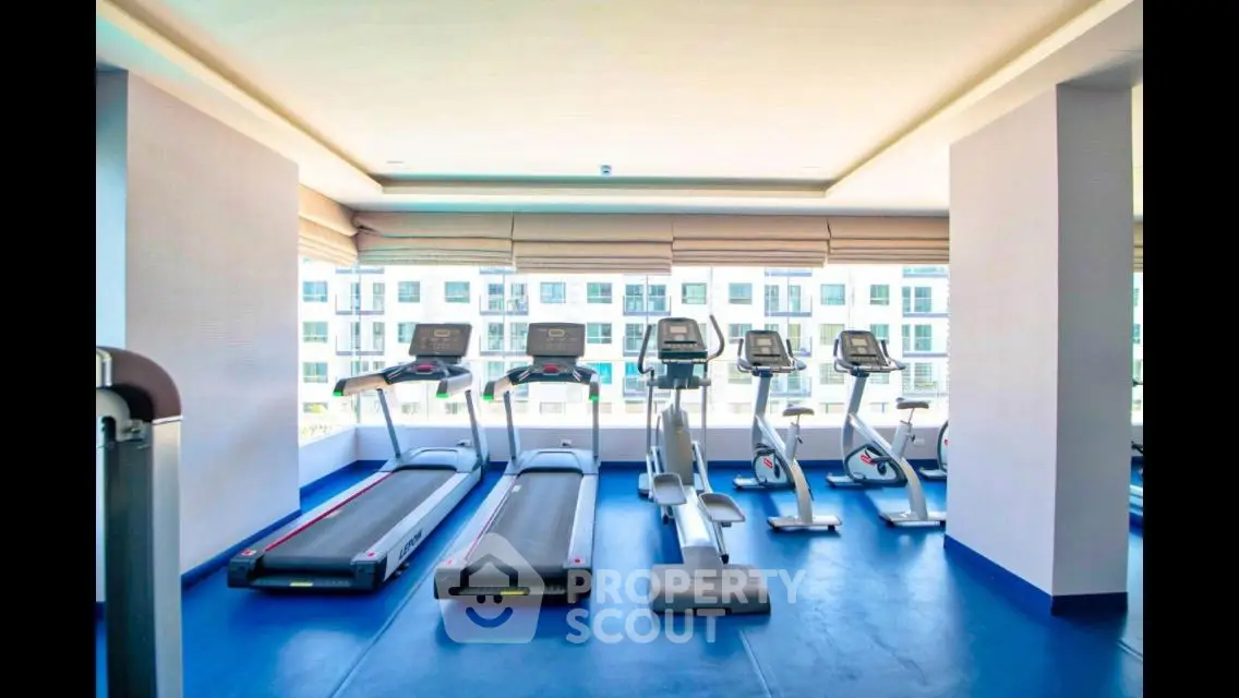 Modern gym with treadmills and exercise bikes in a bright, spacious room.