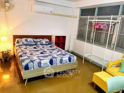 Cozy bedroom with modern decor and ample natural light, featuring a stylish bed and vibrant furnishings.