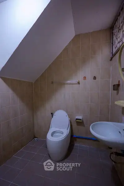 Cozy bathroom with modern toilet and sink under sloped ceiling