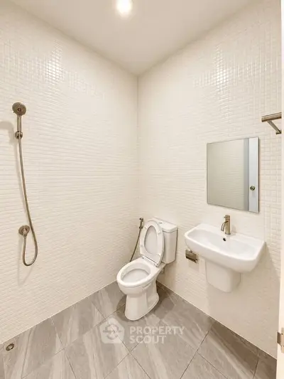 Modern minimalist bathroom with sleek fixtures and tiled walls.