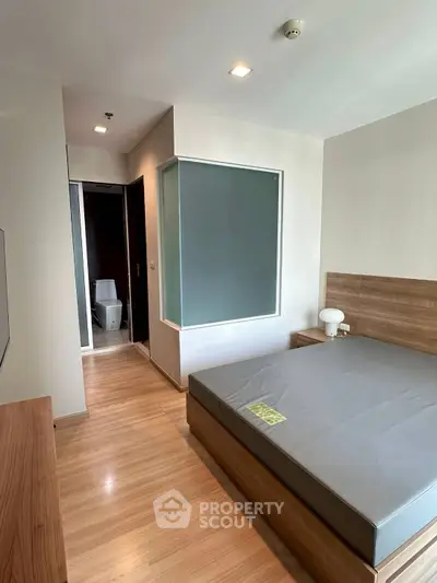 Modern bedroom with wooden flooring and sleek design, featuring a cozy bed and ambient lighting.