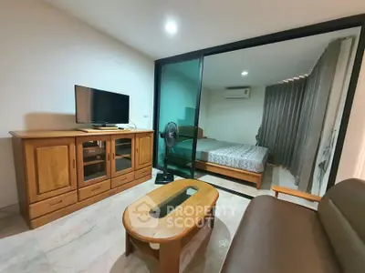Modern living room with wooden furniture and glass partition to bedroom